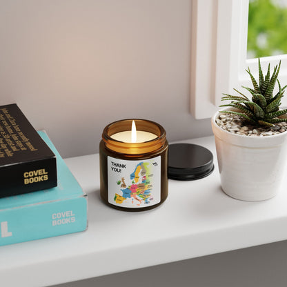 Lit Thank You map candle on a windowsill beside books and a small plant